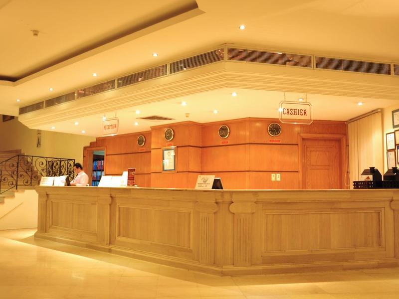 Heller Hotelempfangsbereich mit einer großen Holztheke und mehreren Mitarbeitern