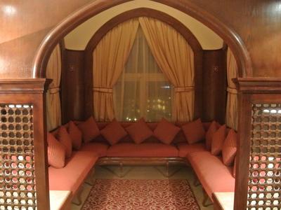 Gemütliche Sitzecke mit roten Kissen, Teppich und Vorhängen in warmem Holzbogen eingerahmt.