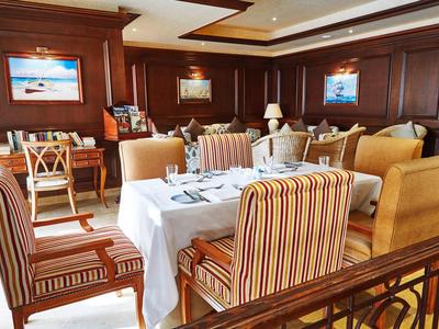 Elegantes Restaurant mit Holzwänden, gestreiften Sesseln und weiß gedecktem Tisch.