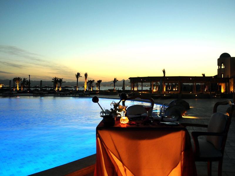 Weicher Sandstrand mit klarem, hellem Wasser und intensiv blauem Himmel am Horizont.