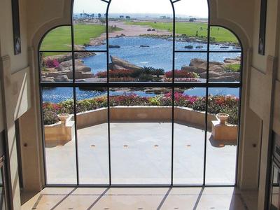 Large arched window overlooking terrace, garden, and sea beyond