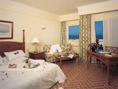 Cozy hotel room with bed, sofa, desk, and terrace overlooking the sea.