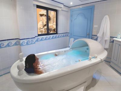Woman relaxing in modern whirlpool bathtub in an elegantly designed bathroom with blue and white decor.