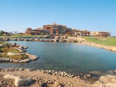 Velký resort s rybníkem a zelenými trávníky pod jasnou modrou oblohou