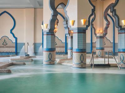 Interno di un hotel ispirato al Marocco con colonne ad arco e una piscina.