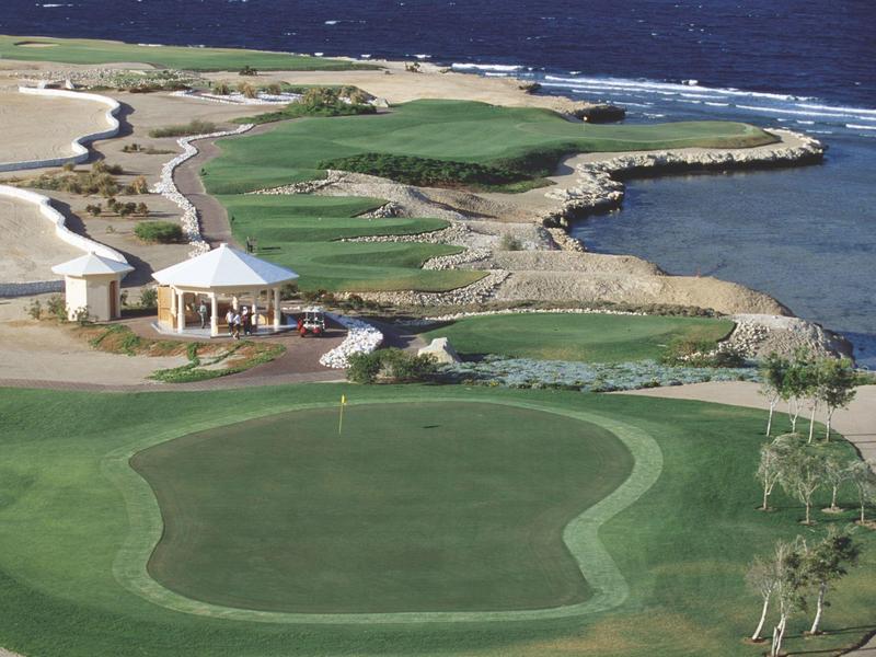 Coastal golf course with multiple greens and a small pavilion