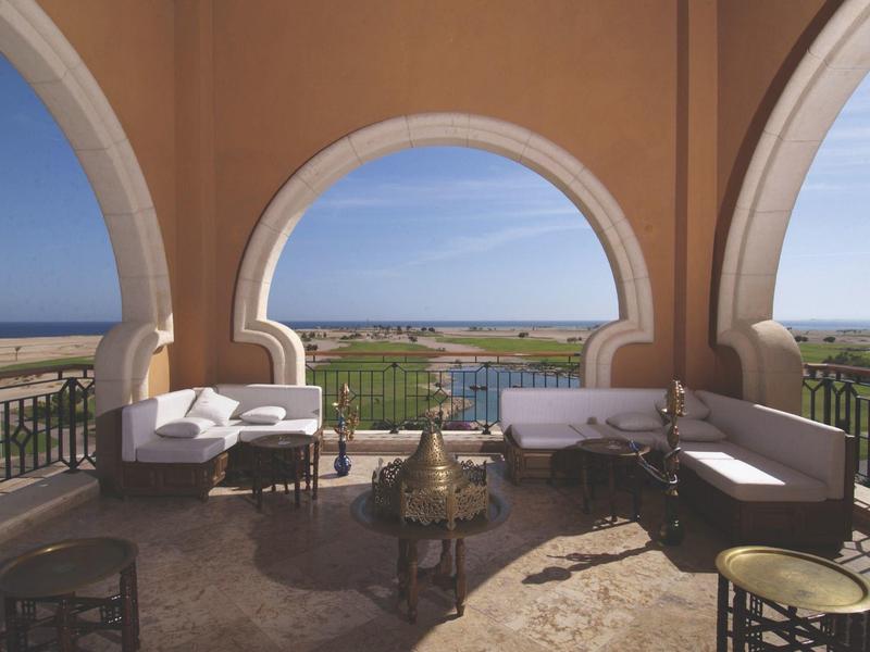 Terrace with elegant arches overlooking landscape, white sofas, and tables.