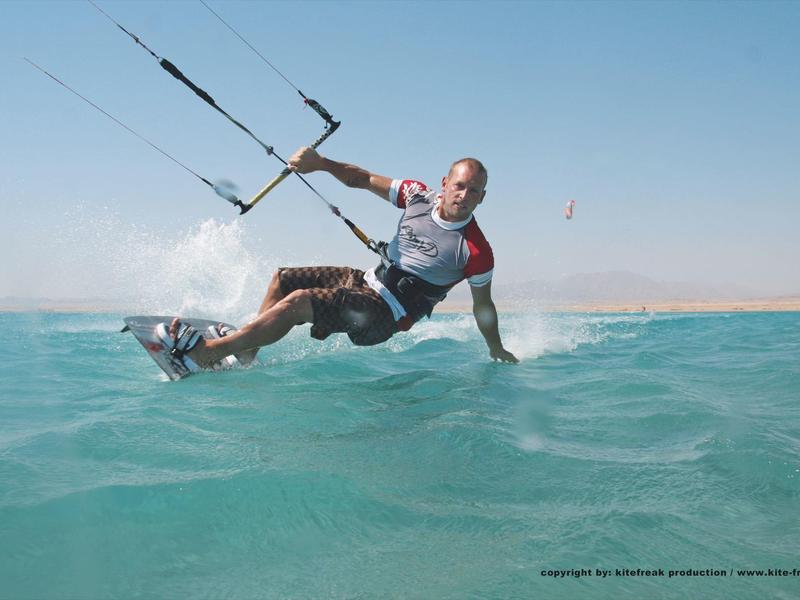 Man kite surfing on blue sea under clear sky.
