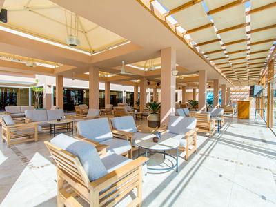 Terrazza dell'hotel moderna con mobili in legno e cuscini blu sotto una copertura in vetro