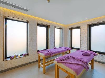 Sala spa luminosa con lettini da massaggio e grandi finestre che danno sull'esterno.