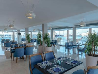 Ristorante moderno con sedie blu e grandi finestre con vista sul mare.