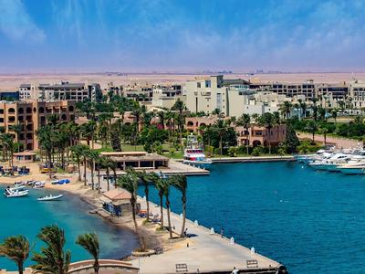 View of a coastal city with hotels, beach, marina, and clear blue water.