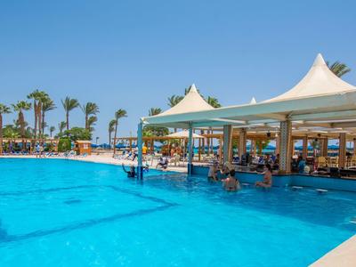 Großer blauer Pool mit barähnlichem Pavillon, Palmen und klarem Himmel im Hintergrund.