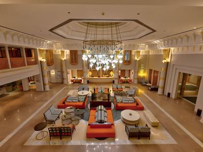 Spacious hotel lobby with seating areas, chandeliers, and warm lighting.