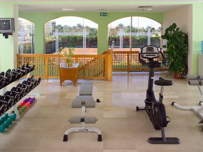 Gym with dumbbells, exercise equipment, and view of a terrace with plants.