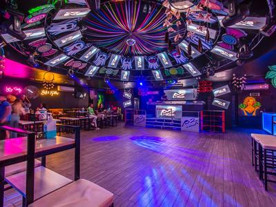 Colorful bar with dance floor, seating areas, and modern lighting in a hotel club.