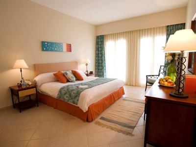 Espace salon d'hôtel confortable avec coussins colorés, fauteuils, canapé, lampes et décoration murale.