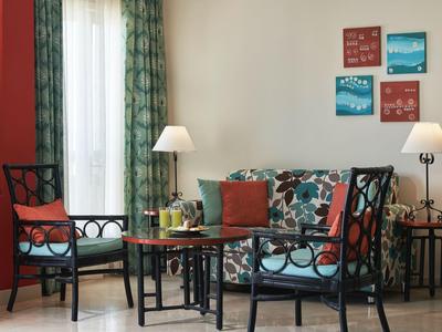 Pohodlný posezení s barevnými židlemi, pohovkou a lampami v hotelovém pokoji.