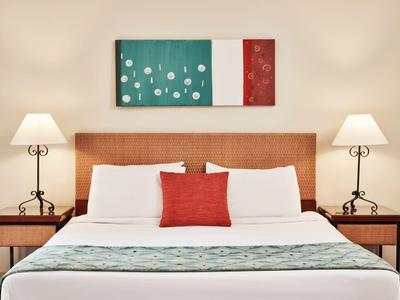 Modernes Hotelzimmer mit Doppelbett, Nachttischen, Lampen und abstrakter Wandkunst.