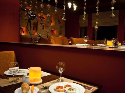 Table de restaurant chaleureuse et tamisée pour deux avec assiettes et une bougie jaune.