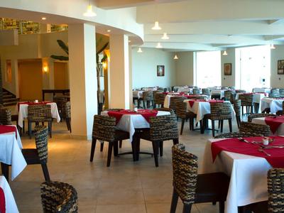 Sala da pranzo luminosa con tovaglie rosse e bianche e sedie intrecciate.