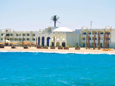 Hotel sulla spiaggia con acqua blu e architettura bianca sotto un cielo limpido.
