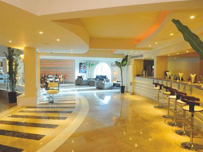 Ampia hall dell'hotel luminosa con bar, sgabelli e area salotto alla luce del giorno.