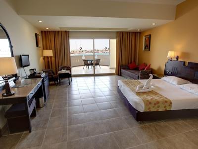 Camera d'hotel luminosa con letto matrimoniale, TV a schermo piatto e balcone con vista mare.