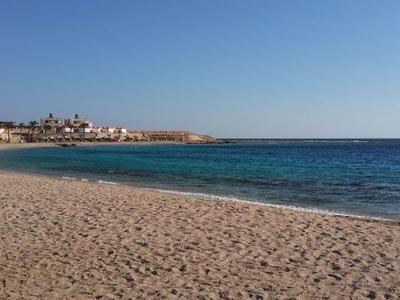 Breid zandstrand met heldere lucht en kalme zee, kustlijn op de achtergrond