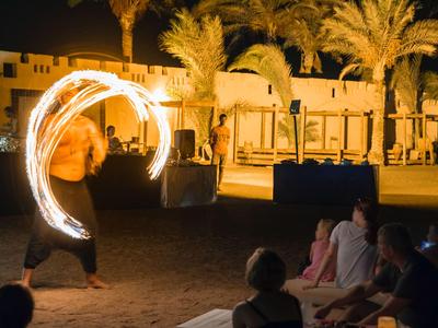 Vuurartiest voert nachtshow uit op strand met palmbomen voor publiek.