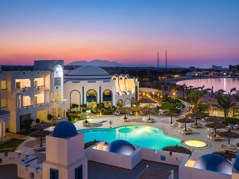 Resort illuminato con piscina e giardino al tramonto sul mare
