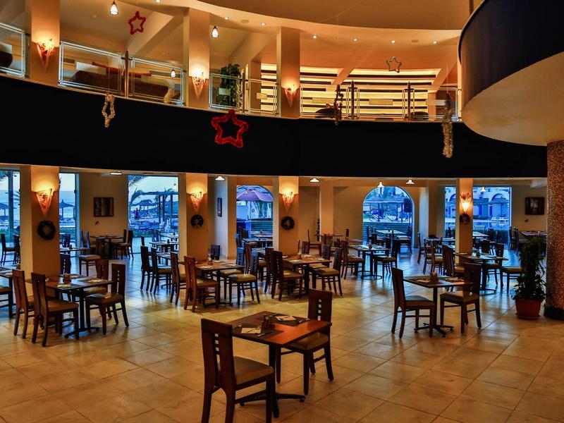 Ampia e luminosa sala da pranzo con molti tavoli e sedie in legno in un hotel.