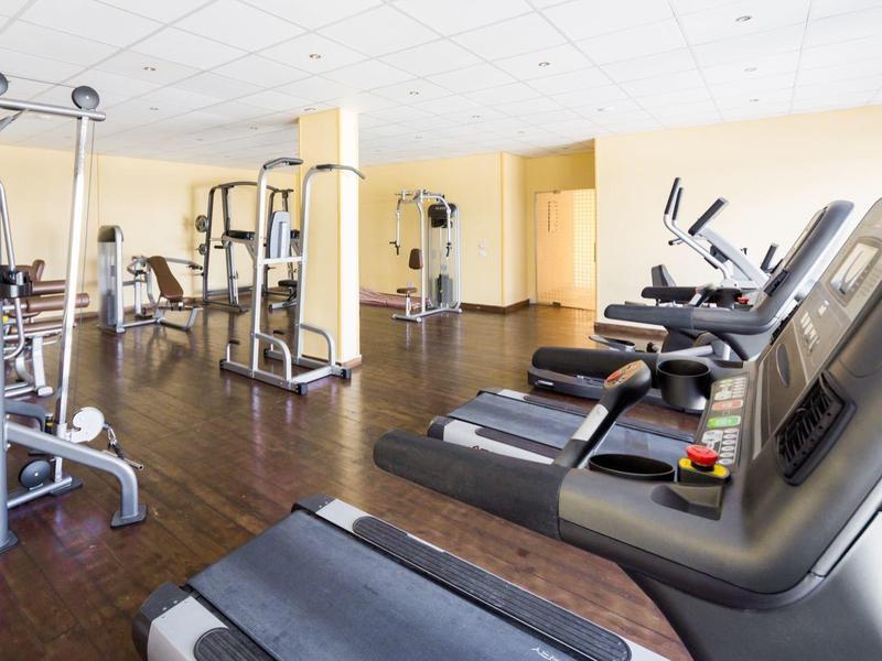 Ampia palestra con attrezzature moderne e tapis roulant su pavimento in legno scuro.