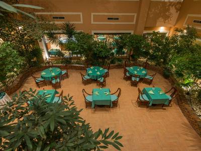 Bovenaanzicht van een tuingebied met groene tafels en stoelen in een hotel.
