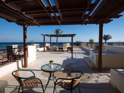 Zonnig terras met zithoek en uitzicht op zee onder een houten pergola.