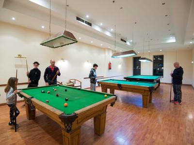 Several people playing billiards in a bright room with wooden flooring.