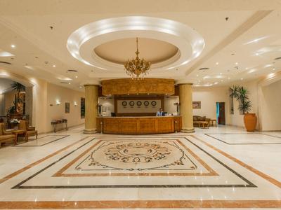 Elegant hotel lobby with large marble floor and decorative reception desk.