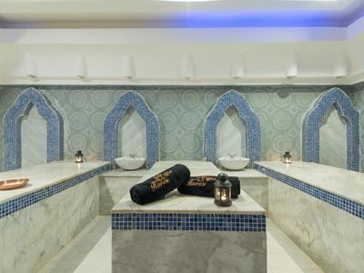 A luxurious Turkish hammam with marble walls and massage tables.