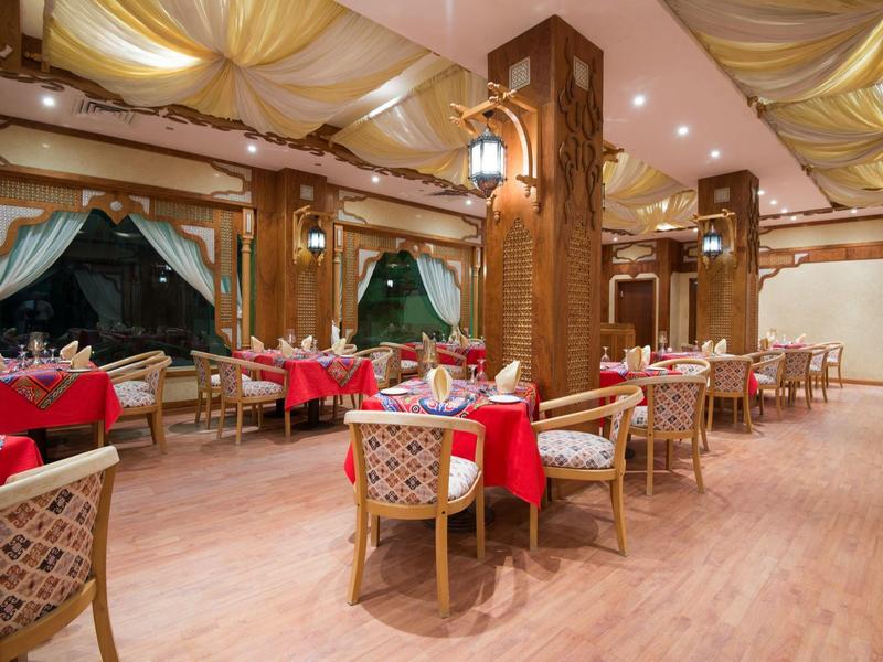 Elegant restaurant met houten vloer, rode tafelkleden en gezellige stoelen.