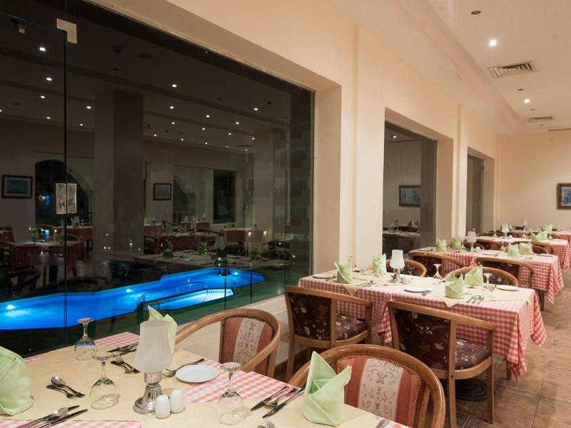 Gezellige hotel eetruimte met gedekte tafels en uitzicht op verlicht zwembad.