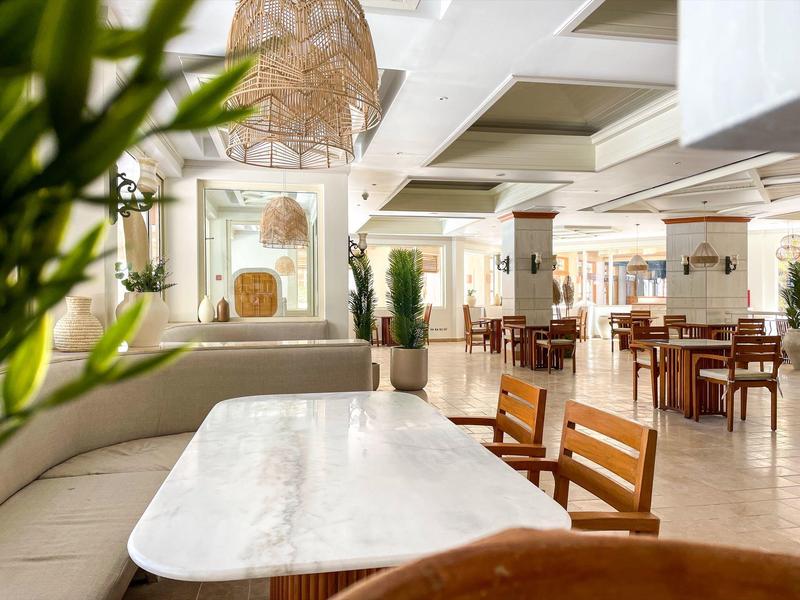 Helles, modernes Hotelrestaurant mit weißen Wänden und Holzstühlen in ruhiger Atmosphäre.