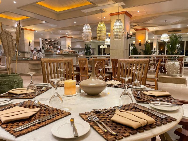 Eleganter Esstisch mit braunen Platzsets, Besteck, Gläsern und Kerze in warm beleuchtetem Raum.