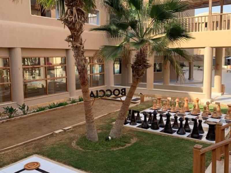 Außenbereich mit Palmen, großem Schachspiel und Backgammon auf einem weißen Brett.