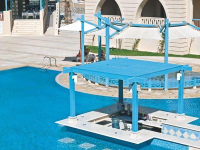 Luxe hotelzwembad met swim-up bar en helder blauw water onder een zonnige lucht.