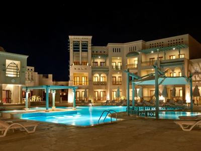 Nachtzicht op een groot hotel met verlicht zwembad en ligstoelen