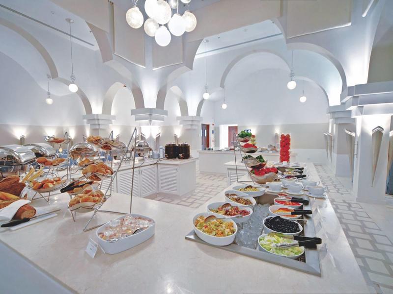 Licht buffet in een ruime eetzaal met elegante bogen en witte inrichting.