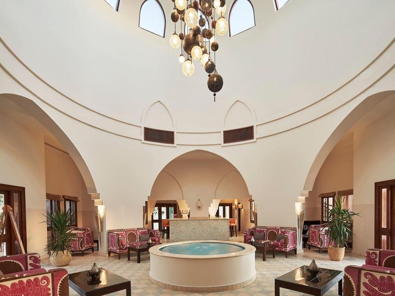 Elegante lounge met koepelplafond, kroonluchter, ronde fontein en stijlvolle zithoek.