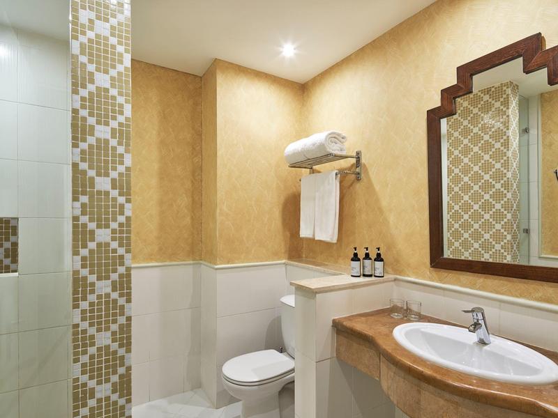 Gezellige badkamer met toilet, wastafel, spiegel, handdoekrek en decoratieve betegelde douche.