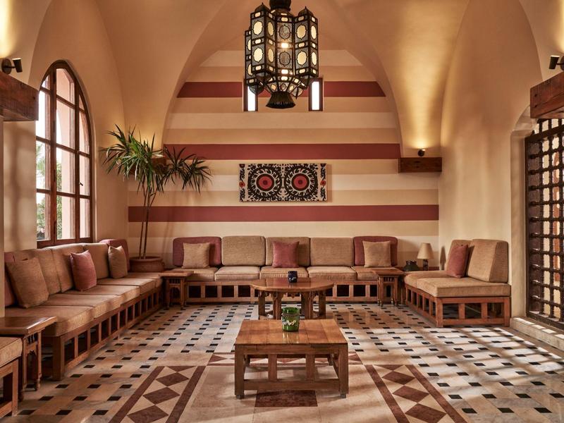 Salon chaleureux avec meubles en bois, tapis à motifs et lanterne suspendue aux tons chauds.