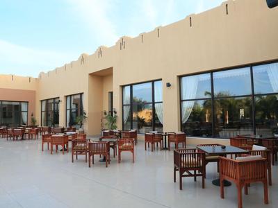 Terrazza dell'hotel con sedie e tavoli in legno davanti a un edificio con grandi finestre.